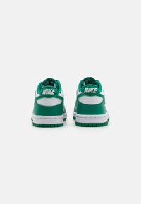 Grønne og hvite Nike-sneakers med en glatt læroverdel, polstret krage og teksturert gummi såle, med fremtredende merkevare på hælen.