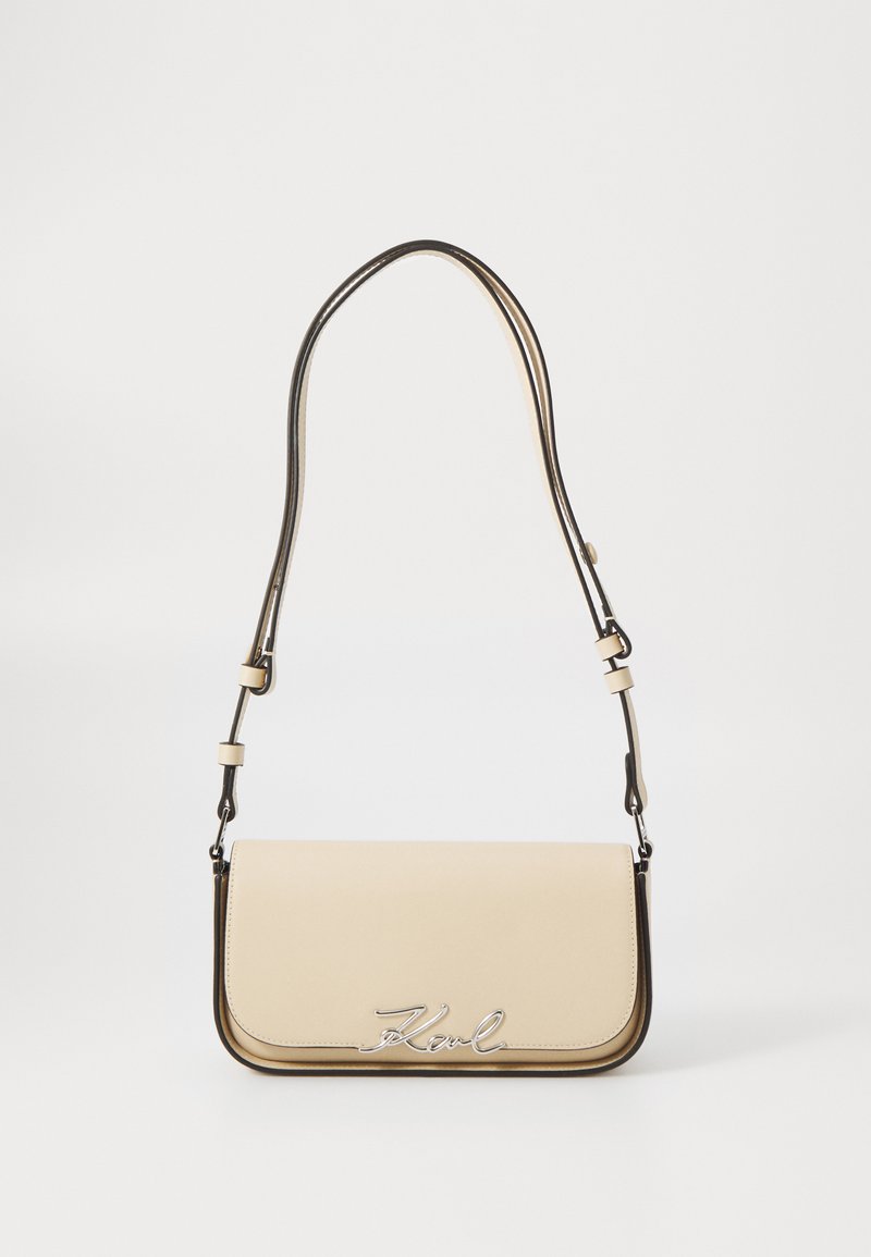 Borsa a tracolla in pelle beige con un design sottile, caratterizzata da un logo argento, finiture a contrasto e una tracolla regolabile.