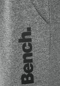 Graue, strukturierte Sweatpants aus Stoff mit einem schwarzen "Bench."-Logo an der Seite und einer Vordertasche für Funktionalität.