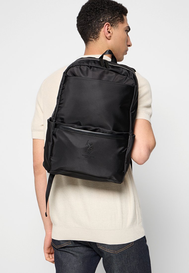 Černý nylonový batoh s logem, kapsami na zip, polstrovanými popruhy a elegantním obdélníkovým designem. Hladký povrch, minimální detaily.