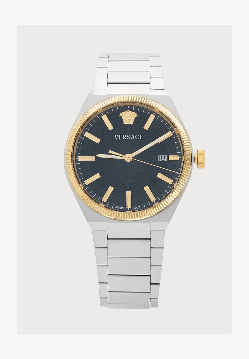 Montre-bracelet en métal argenté avec cadran noir, lunette dorée, index dorés, affichage de la date à trois heures et logo "Versace" sous midi.