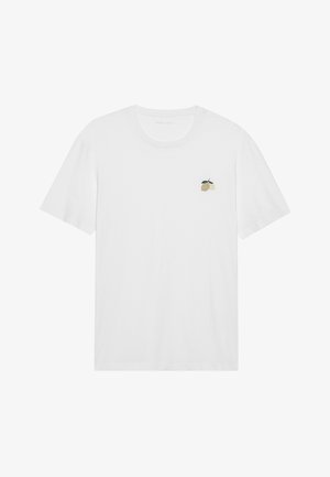 Tricou alb din bumbac, cu guler rotund și mâneci scurte. Are un mic design brodat cu o lămâie pe partea stângă a pieptului. Design simplu.