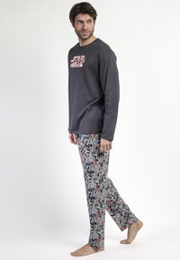 Camisa de manga larga gris con un estampado gráfico en rojo y blanco; pantalones de pijama con patrón en negro, gris y rojo que presentan varios diseños.