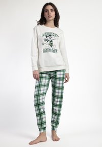 Maglietta bianca a maniche lunghe in cotone con stampa di Topolino verde, abbinata a pantaloni del pigiama a righe verdi e bianche con elastico in vita.