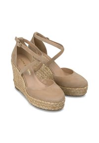 Sandales compensées en suède beige avec des brides croisées autour de la cheville et une plateforme en jute. Bout rond et texture lisse. Nom de la marque visible à l'intérieur.
