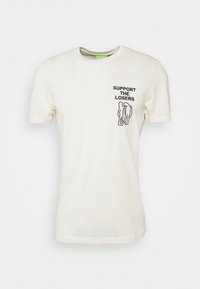 Kremowa bawełniana koszulka z krótkim rękawem, z czarnym nadrukiem graficznym przedstawiającym dwie postacie oraz napisem "WSPIERAJ PRZEGRANYCH" na klatce piersiowej.