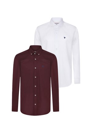 Dos camisas de botón de manga larga: una burdeos con una textura suave y botones blancos, la otra blanca con una sutil textura tejida y un logo azul.