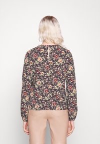 Blouse fleurie à manches longues en tissu foncé avec des fleurs jaunes et rouges. Dotée d'une ouverture en forme de goutte au dos et de manches ajustées avec poignets.