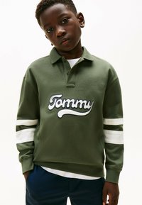 Groene langetermijn polo met een witte geborduurde "Tommy" logo. Bevat witte strepen op de mouwen, een kraag en een ontspannen pasvorm.
