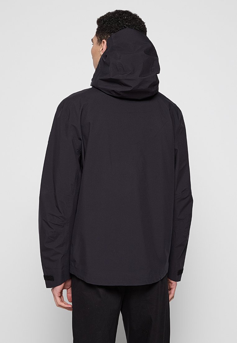 Giacca nera impermeabile con cappuccio, caratterizzata da una texture liscia e opaca e da polsini regolabili, progettata per l'uso all'aperto.
