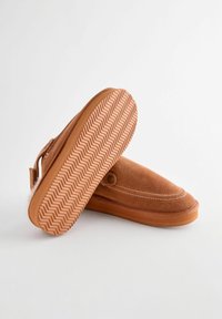 Brune ruskinds-sandaler med rund tå og hvid syning, der har en struktureret gummisål med et fiskebensmønster.