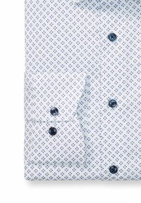 Weißes Hemd mit einem sich wiederholenden blauen Blumenmuster, ausgestattet mit einem Button-Down-Kragen und Manschetten sowie dunkelblauen Knöpfen.