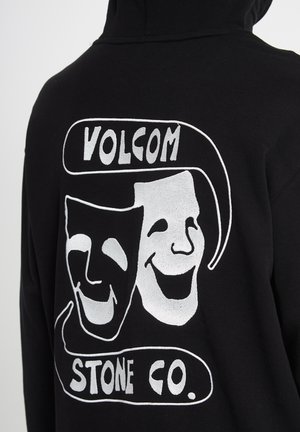 Czarna bluza z kapturem z białymi teatralnymi maskami komedii i tragedii oraz napisem "Volcom Stone Co." na plecach.