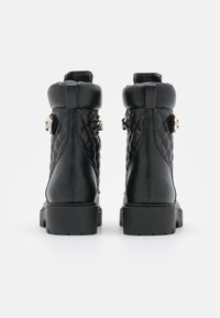 Sorte læderankelstøvler med quiltet tekstur, kraftig gummisål og guldfarvede hardware-detaljer på siderne.