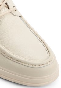 Krämfärgade lädersneakers med rundad tå, ton-i-ton-sömmar och en slät yta. Diskreta detaljer inkluderar snörhål och en vadderad sula.