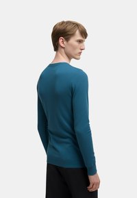 Maglione a maniche lunghe teal in maglia con scollatura rotonda, polsini e orlo a coste, texture liscia, design aderente e stile minimalista.