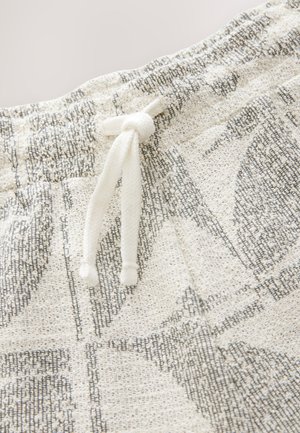 Hvidt og gråt mønstret stof med en tekstureret finish, udstyret med en hvid snor til justering ved taljen.