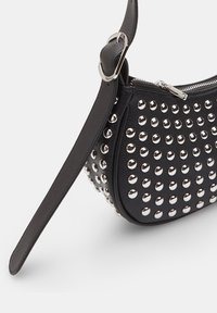 Borsa in pelle nera con borchie argentate, forma curvata, chiusura con zip e tracolla regolabile. Caratterizzata da una superficie texturizzata e dettagli lucidi.