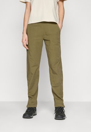 Olivegrüne Hose aus leichtem, strukturiertem Stoff mit geradem Schnitt, seitlichen Taschen und verstärkten Knien. Kombiniert mit schwarzem Schuhwerk.