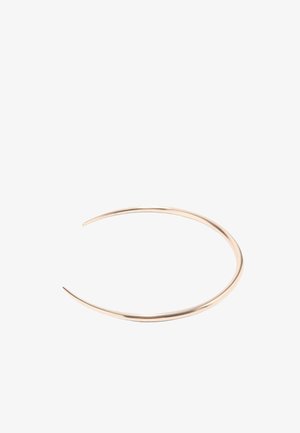 Bracciale sottile in metallo dorato aperto con un design liscio e curvo su sfondo bianco.