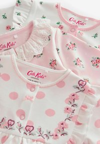 Trois robes d'enfants en coton doux. L'une a des pois roses, une autre présente des motifs floraux, et la troisième arbore des bords volants et de la broderie.
