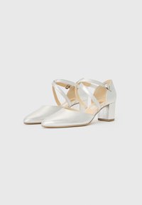 Silver metallic high-heeled shoes with a pointed toe, featuring crisscross straps and a block heel design. Smooth texture and minimalist style.