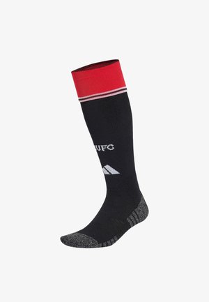 Czarna sportowa skarpeta do kolan z czerwonym mankietem, białymi paskami, białym napisem "MUFC", logo Adidas oraz szarymi teksturowanymi obszarami na pięcie i palcach.