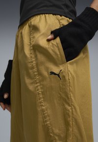 Gule, letvægts shorts med en glat finish og en elastisk talje; har et sort Puma-logo og en hånd i en sort fingerløs handske.