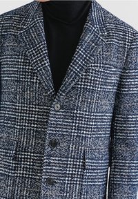 Marineblauw-wit geruit colbert met inkeping revers, drie knopen en gestructureerde stof; voorzien van een borstzak en twee voorzakken.