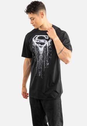 Black cotton t-shirt featuring a dripping white Superman logo graphic on the front. Short sleeves and a relaxed fit.