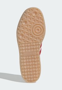 Podešev gumové boty světle pískové barvy, s texturovaným vzorem obsahujícím geometrické tvary a tři kruhové motivy; embossováno logem "adidas".