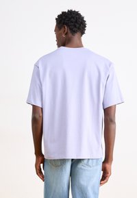 Lilla bomulds T-shirt med afslappet pasform, rund halsudskæring og korte ærmer. Bagview viser en glat tekstur og minimale syninger.