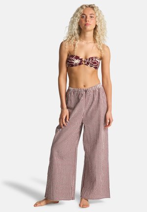 Bikinitop in bordeauxrood met wit abstract patroon; wijde broekspijpen in geruit bordeauxrood-wit stof; ontspannen pasvorm met elastische tailleband.