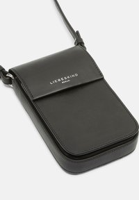 Sac bandoulière en cuir noir avec une texture lisse, de forme rectangulaire, fermeture à rabat magnétique et logo embossé à l'avant.