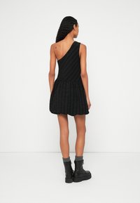 Melna, vienas pleca kleita ar teksturētu rakstu, izplūdušu svārku un cieši pieguļošu korseti. Valde kopā ar melniem kaujas zābakiem un pelēkām adītām aprocēm.