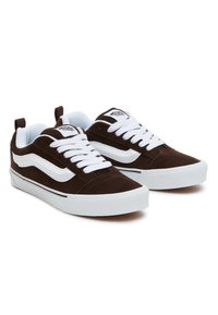 Brune suedesneakers med hvite snører, en hvit sidestrek, og en gummisåle med svarte detaljer. Lett og lavt design.