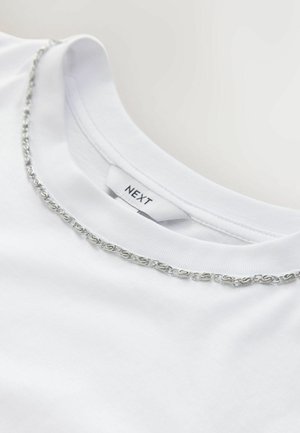 Valkoinen puuvillainen t-paita, jossa on pyöreä kaula-aukko ja hopeaketjuun koristeltu kaulus. Labelissa lukee "NEXT". Pehmeä koostumus.