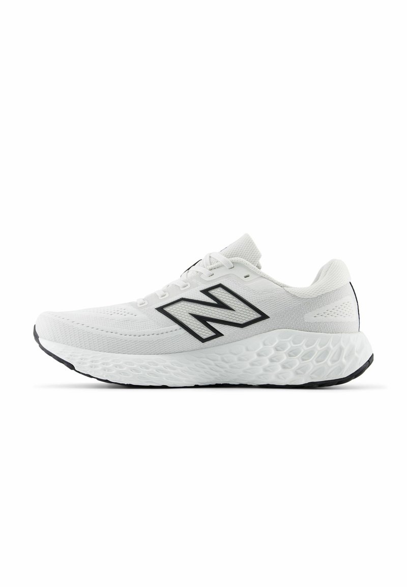 Zapatilla deportiva blanca con parte superior de malla, puntera redondeada, acentos negros y suela con acolchado texturizado. Presenta un prominente logo 'N' en el lateral.