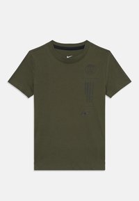 Camiseta de algodón verde oliva con cuello redondo, mangas cortas, logo negro de Nike y emblema y texto de París impresos en la parte frontal.