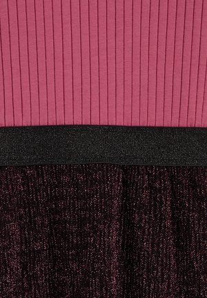 Kjolen har en ribbet pink top, et sort glitrende taljebånd og en svingende nederdel i et mørkt skimrende stof. Materialernes kontraster fremhæver strukturen.