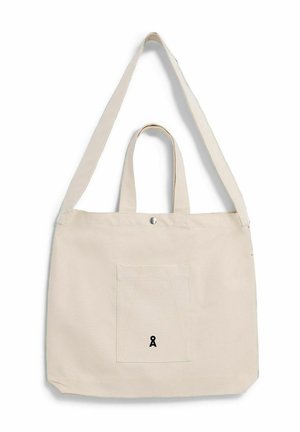 Beige Leinentasche mit Fronttasche, kurzen Griffen, langem Schulterriemen und kleinem schwarzen Logo mittig auf der Tasche.