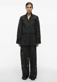 Ensemble en dentelle noire comprenant une veste ouverte à motifs floraux avec un col et un pantalon ample, rehaussé d'un liseré noir lisse.
