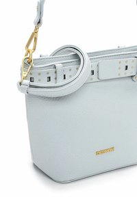 Jasnoniebieska skórzana torebka o usztywnionym kształcie, wyposażona w odpinany pasek, złote okucia oraz ozdobny pasek z złotymi kropkami.