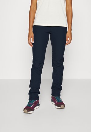 Marineblaue, leichte Hose im Slim Fit mit dezenten reflektierenden Akzenten, kombiniert mit burgunderfarbenen Schuhen und türkisfarbenen Schnürsenkeln.