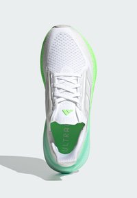Weißer Sportschuh mit einem Obermaterial aus Mesh, grünen Akzenten und einer strukturierten Sohle. Verfügt über Schnürsenkel und Branding auf der Zunge und der Innensohle.