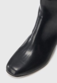 Czarne skórzane botki do kostki o kwadratowym nosie i gładkiej fakturze. Charakteryzują się dopasowaną sylwetką i minimalistycznym designem.