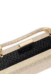 Gold and black handbag with a glittery texture, structured design, a shiny metallic clasp, and a fabric inner lining featuring a pattern.