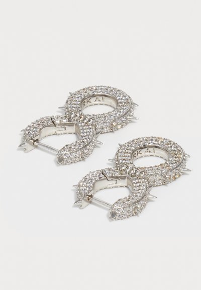 Silver hoop earrings shaped like intertwined serpents, encrusted with clear rhinestones, featuring pointed accents and a hinged clasp.