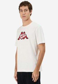T-shirt bianco in cotone con un logo grafico rosso e nero con il testo "MEGLIO INSIEME". Maniche corte e scollo a girocollo.