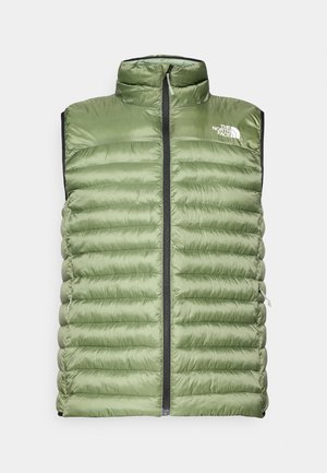 Olīvu zaļa pūkainā veste ar augstu apkakli, priekšējo rāvējslēdzēju un horizontālu izšuvuma rakstu. Uz augšējās kreisās puses ir logo un sānu kabatas.
